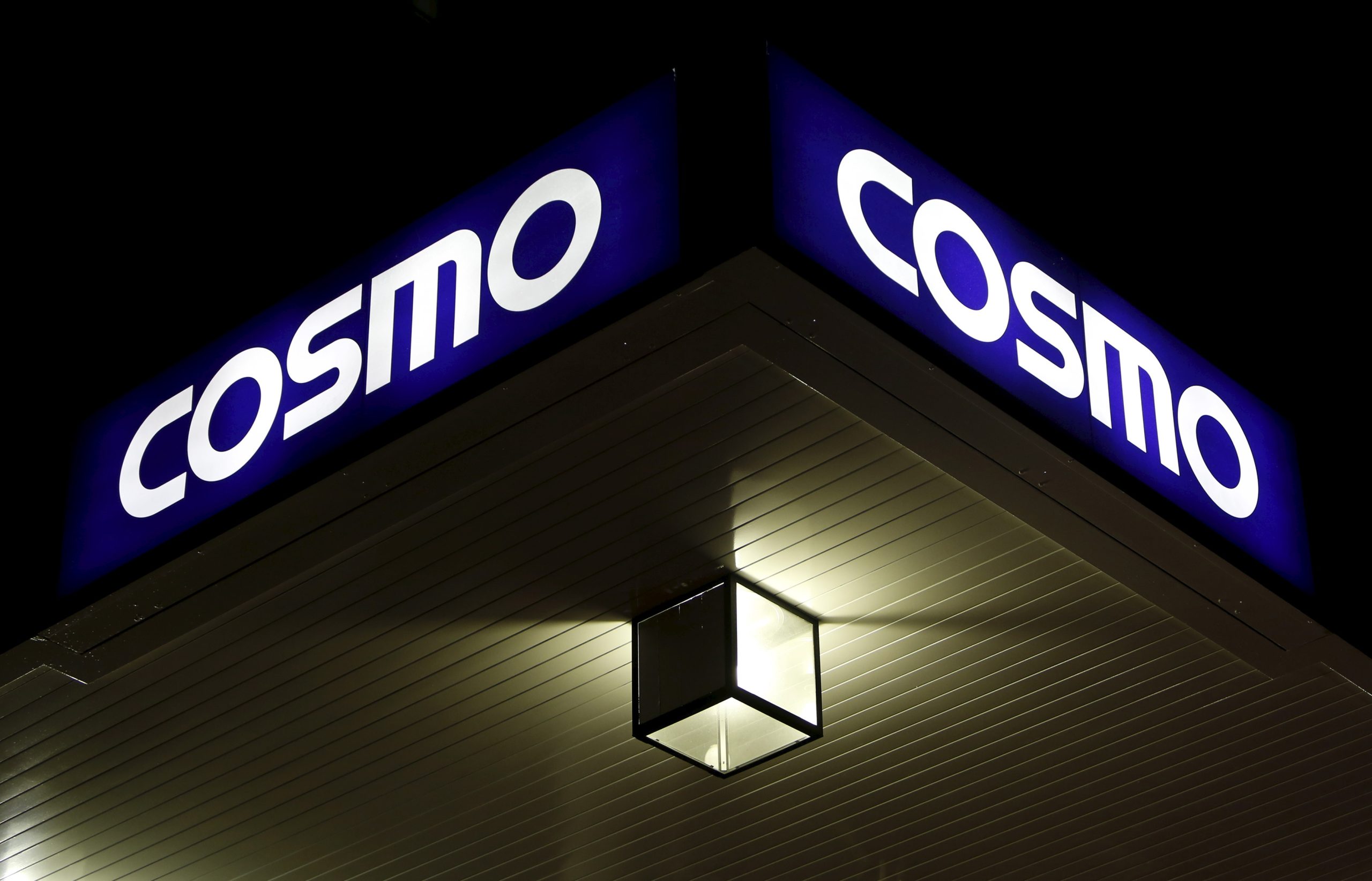 A light is seen under a signboard of Cosmo Energy Holdings' Cosmo Oil service station in Tokyo, Japan