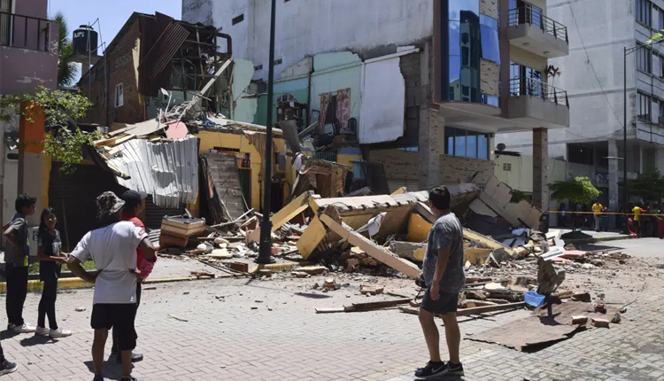 Residents look at a building that collapsed after an earthquake shook Machala, Ecuador, Saturday, March 18, 2023