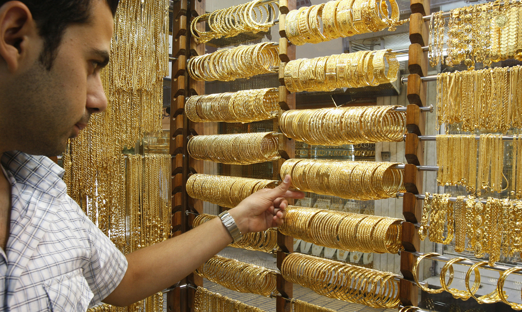 Gold shop owner organizing displayed gold cuffs