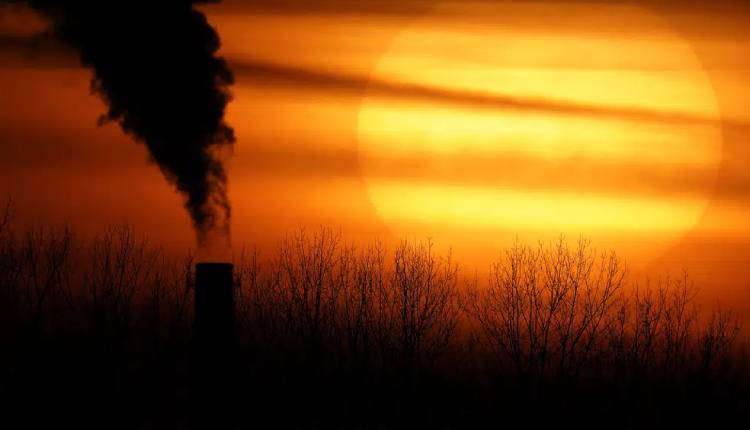 Emissions from a coal-fired power plant are silhouetted against the setting sun in Kansas City, Mo., Feb. 1, 2021