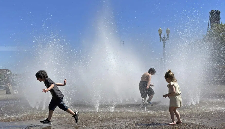 Children play in a fountain to cool off in downtown Portland, Ore., Friday, May 12, 2023