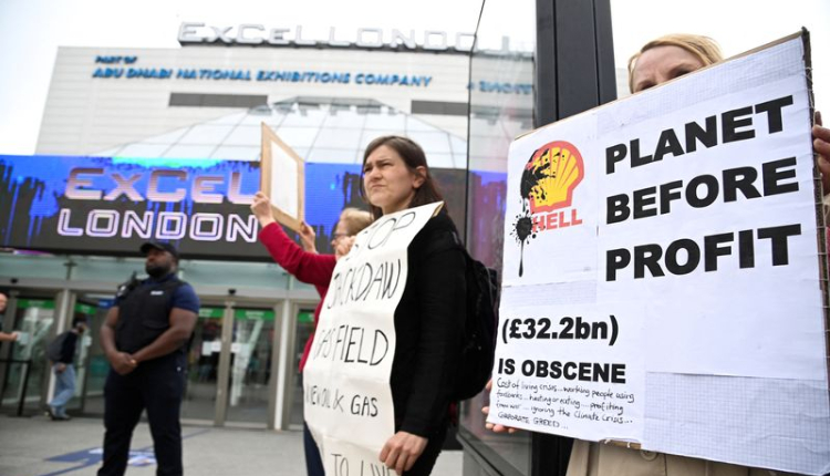 People hold signs as protesters from Fossil Free London demonstrate outside the venue of Shell's annual shareholder meeting, at the ExCeL center, in London, Britain May 23, 2023