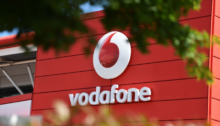 Vodafone sign shadowed with trees on borders